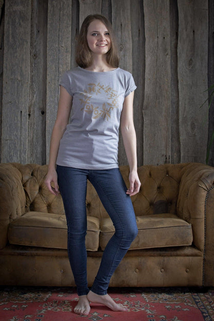 Jauna sieviete, kura apģērbusi sietspiedē apdrukātu gaiši pelēku sieviešu t-kreklu ar sietspiedē apdrukātu bronzas krāsas vainagu. Apdrukāts sietspiedē TingPrint.